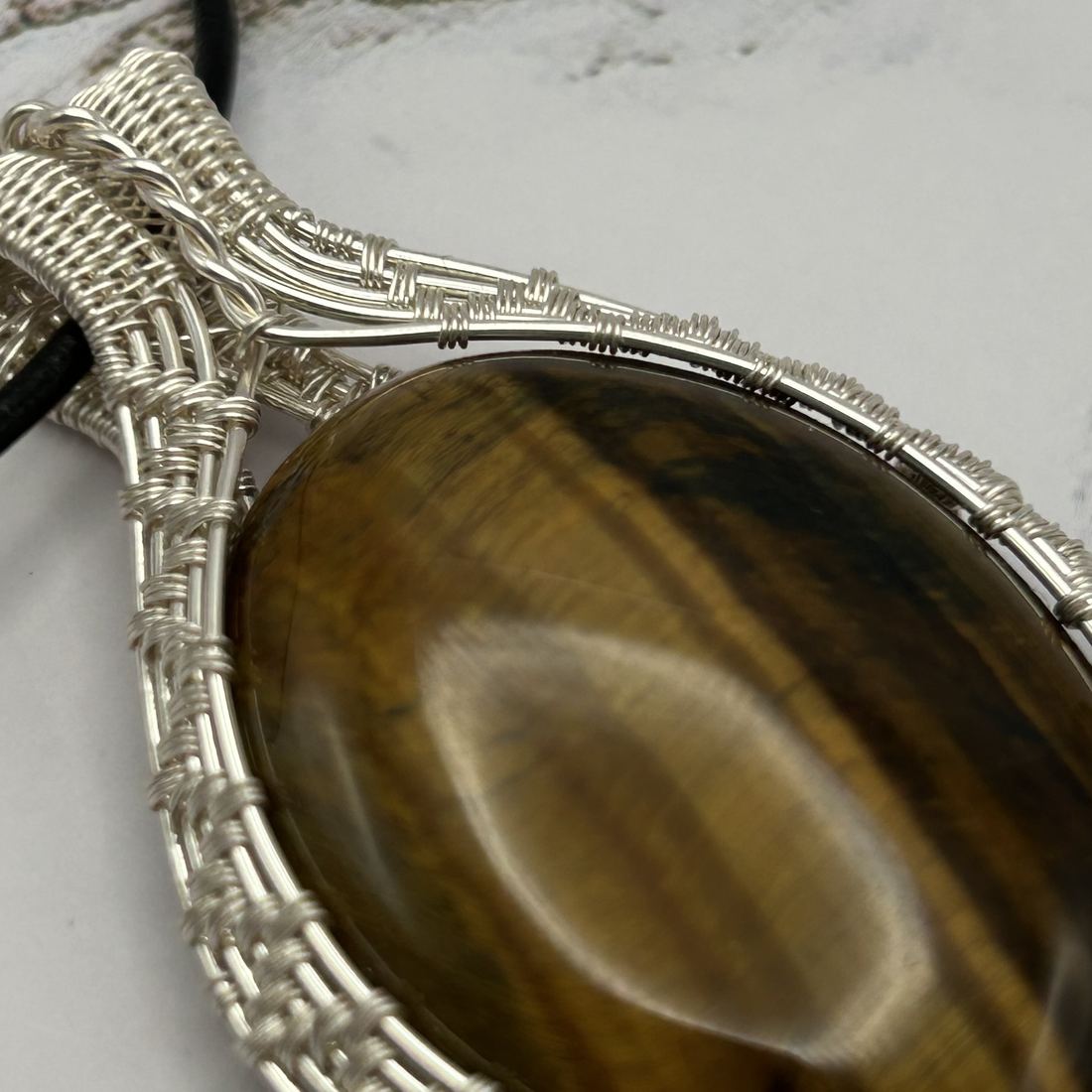 Close-up of the woven silver wire around a tiger eye pendant