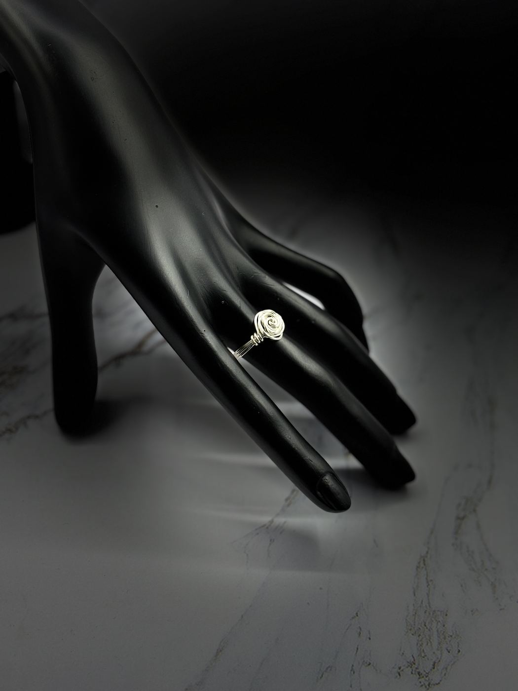 Wire rose ring on a black hand form
